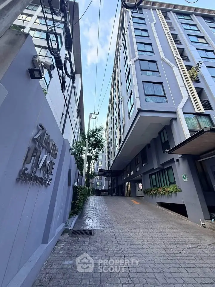 Modern high-rise building exterior with sleek design and spacious driveway entrance.
