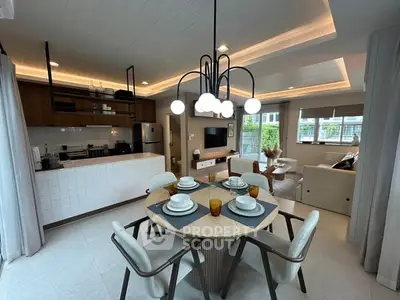 Modern open-layout kitchen and living room with stylish dining area and contemporary lighting.