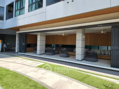 Modern building exterior with stylish outdoor seating area and green landscaping.
