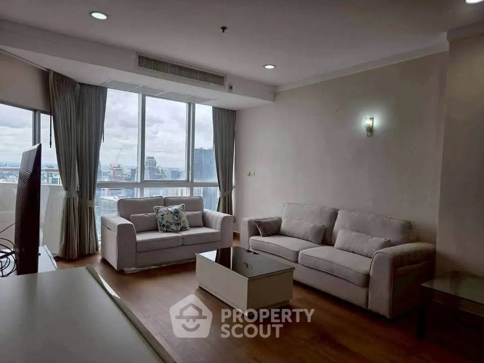 Spacious living room with large windows and modern furniture offering city views.