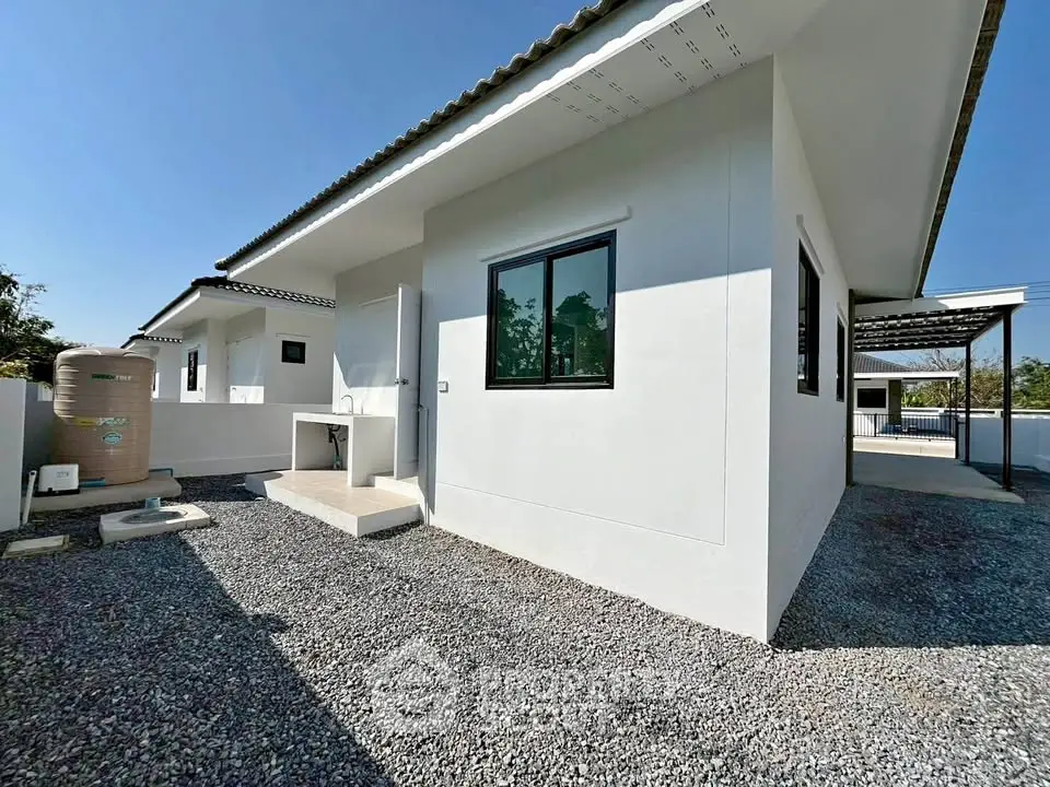 Modern single-story house with clean white exterior and gravel driveway, showcasing minimalist architecture.