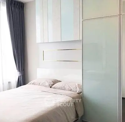 Modern bedroom with sleek design and ample natural light, featuring stylish storage solutions.