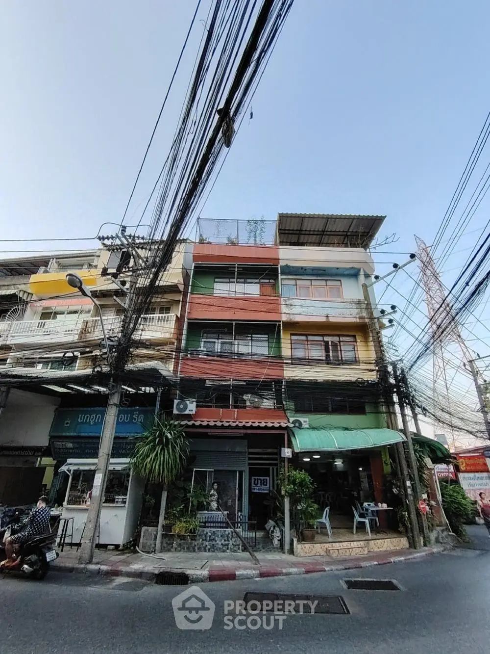 Vibrant multi-story commercial-residential building in a bustling urban area, featuring storefronts on the ground floor and living spaces above.