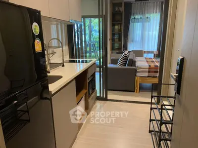 Modern studio apartment with sleek kitchen and cozy living area, featuring large windows and stylish decor.