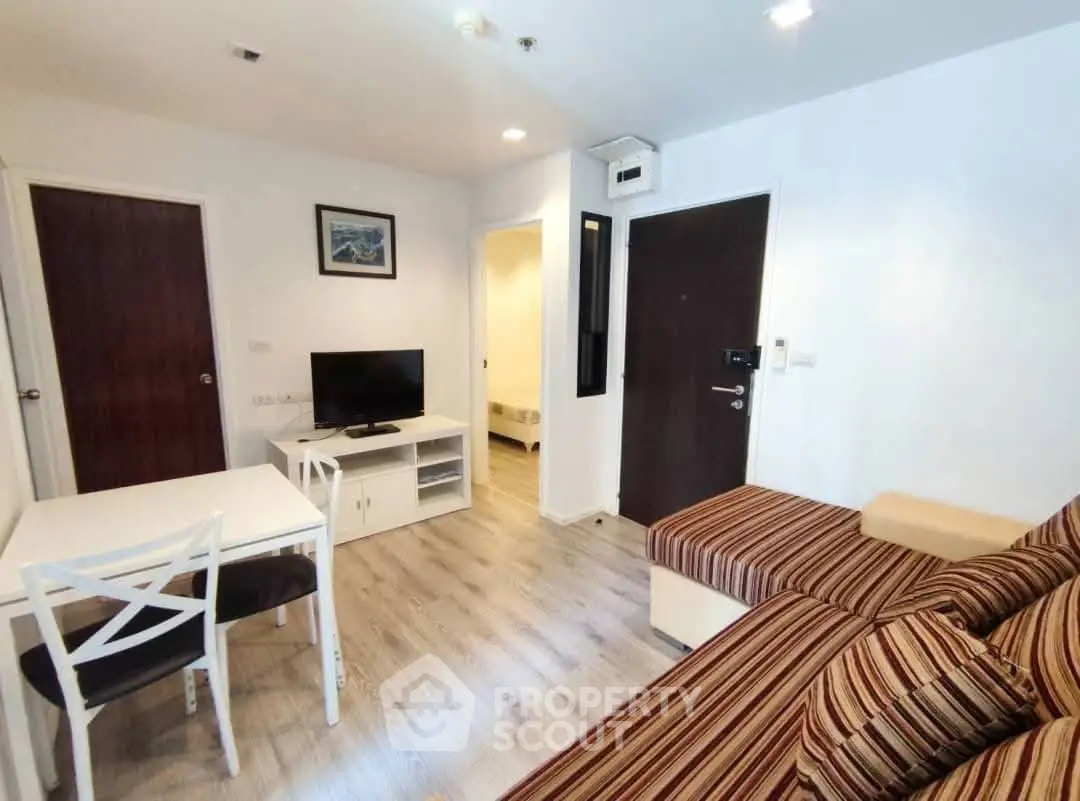 Modern living room with striped sofa, dining table, and TV stand in cozy apartment.