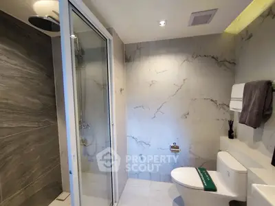 Luxurious bathroom with marble walls and modern shower in upscale property.