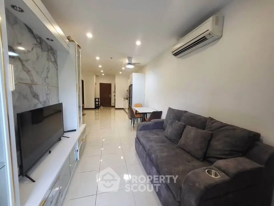 Spacious living room with modern sofa and wall-mounted TV in a stylish apartment.