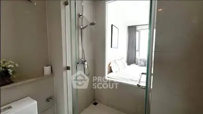 Modern bathroom with glass shower and view into a cozy bedroom