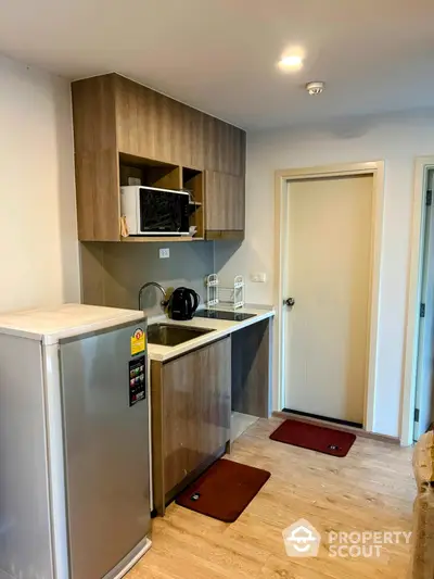 Modern compact kitchen with wooden cabinets and stainless steel appliances in cozy apartment