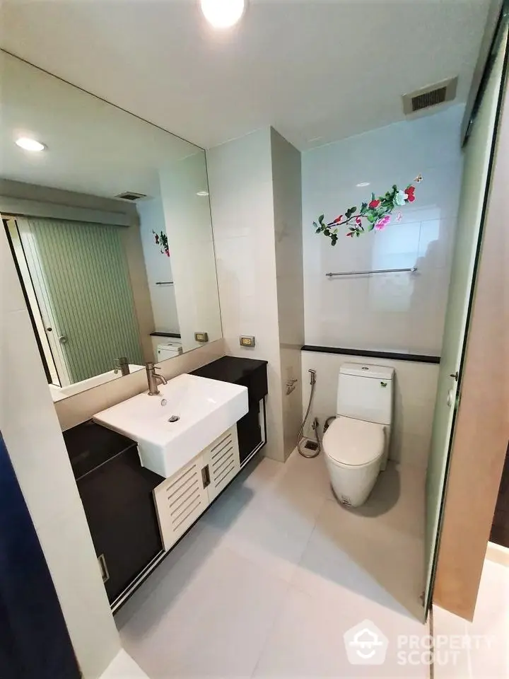 Modern bathroom with sleek fixtures and large mirror in contemporary home.