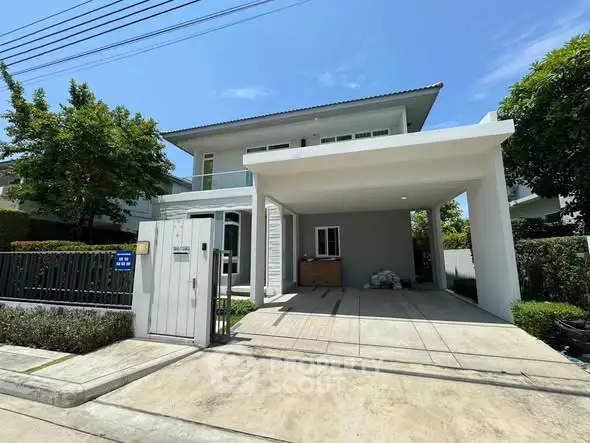 Modern two-story house with spacious driveway and lush greenery in a serene neighborhood.