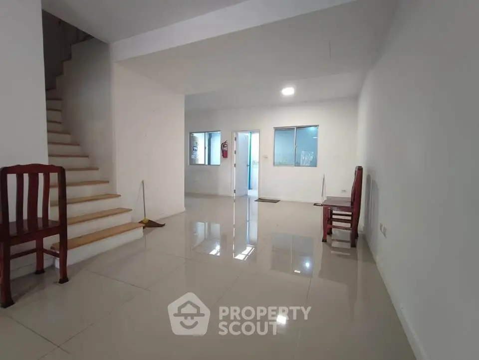 Spacious open-plan living area with glossy tiled floors and staircase, ideal for modern living.