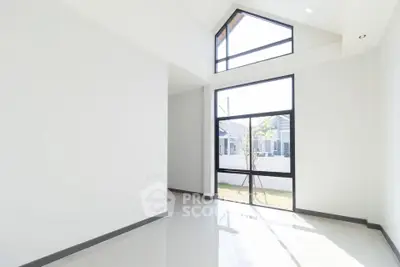 Spacious modern room with high ceiling and large windows offering natural light