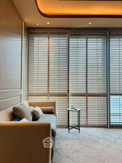 Elegant living room with modern sofa and floor-to-ceiling windows with blinds, offering a serene ambiance.