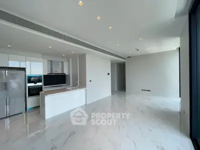 Modern open-plan kitchen with sleek white cabinetry and marble flooring in a luxury apartment.