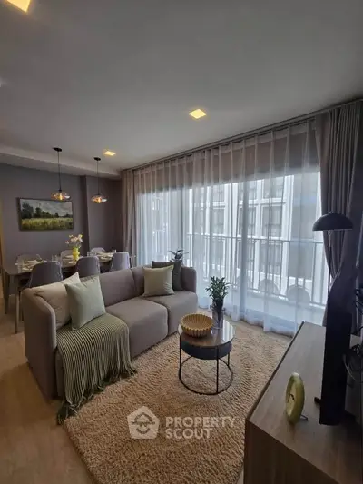 Stylish modern living room with cozy seating and large windows in a contemporary apartment.