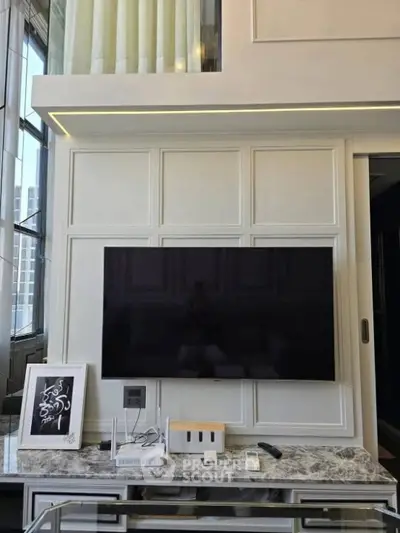 Modern living room with wall-mounted TV and elegant decor in a high-rise apartment.