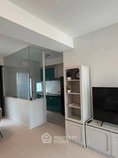 Modern living room with sleek TV setup and view into stylish kitchen