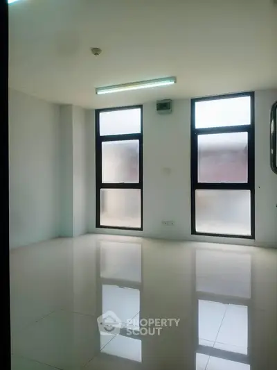 Spacious empty room with large windows and glossy tiled floor, perfect for customization.