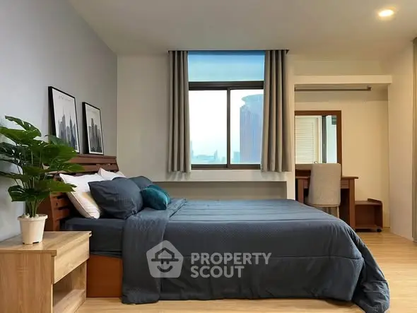 Modern bedroom with stylish decor and city view window, featuring a cozy bed and elegant furnishings.
