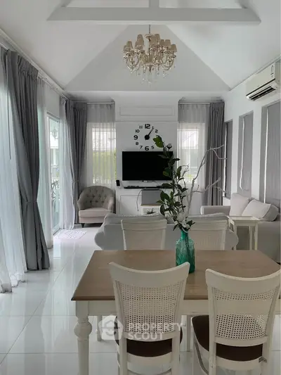 Elegant living room with chandelier, large windows, and stylish decor in a modern home.