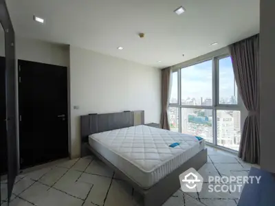 Spacious bedroom with city view and large windows in modern apartment.