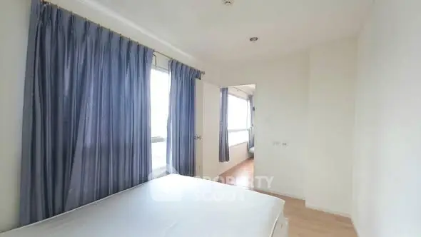 Spacious bedroom with large windows and blue curtains