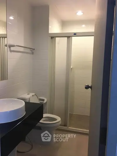 Modern bathroom with sleek fixtures and glass shower enclosure in a contemporary apartment.