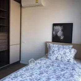 Cozy bedroom with floral bedding and zebra artwork, featuring built-in wardrobe and air conditioning.