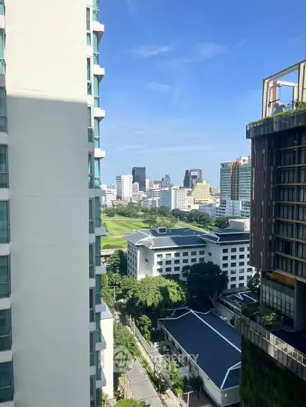 Stunning cityscape view from high-rise building with lush greenery and modern architecture.