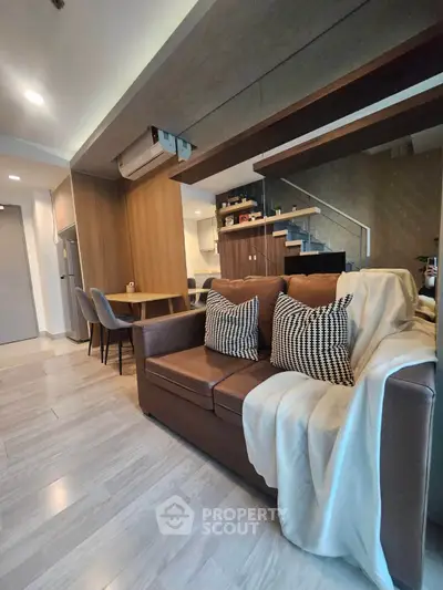 Modern living room with stylish furniture and open layout, featuring a cozy sofa and dining area.