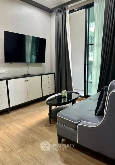 Modern living room with sleek furniture and large TV, featuring a stylish open layout and elegant decor.