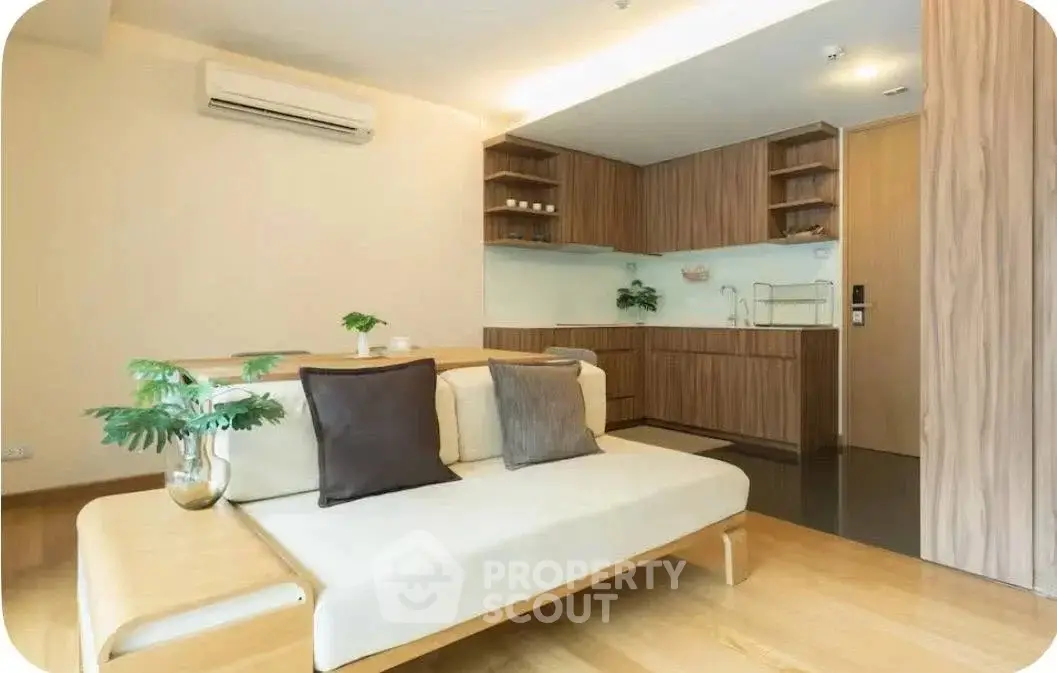 Modern living room with open kitchen, featuring sleek wooden cabinetry and cozy seating area.