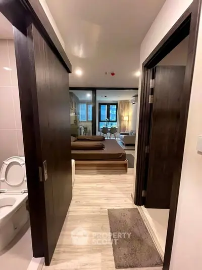 Modern apartment interior with open layout, featuring a cozy bedroom and sleek bathroom entrance.