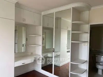Spacious bedroom with built-in mirrored wardrobe and elegant shelving.