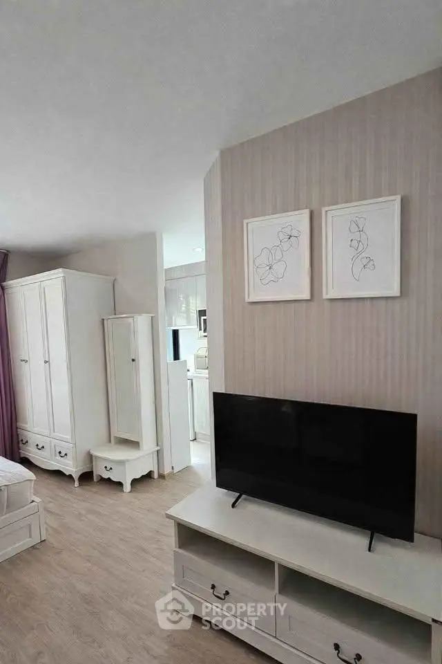 Charming living room with modern decor and flat-screen TV, featuring elegant wooden flooring and stylish furniture.