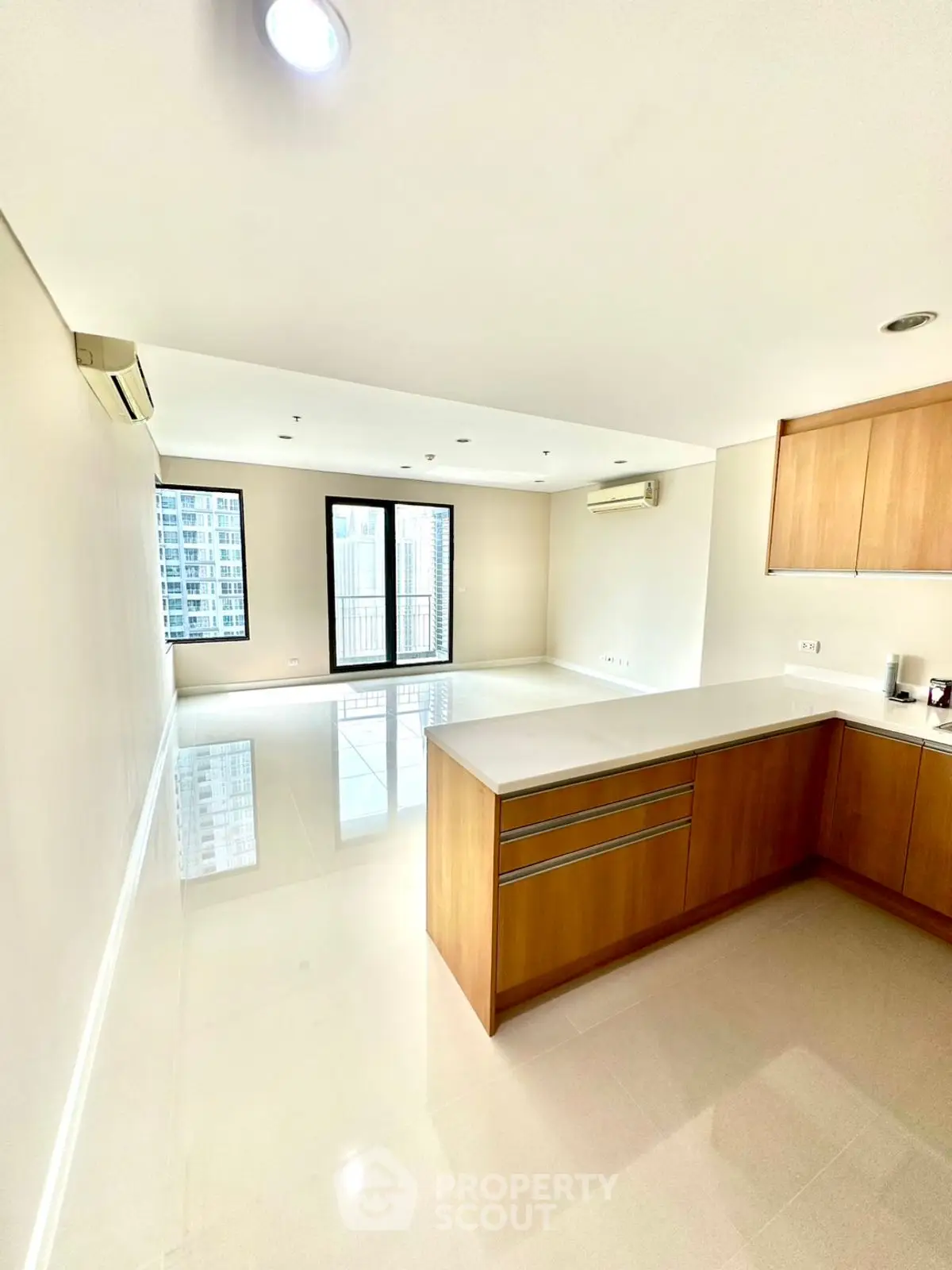 Spacious modern living room with open kitchen and city view balcony.