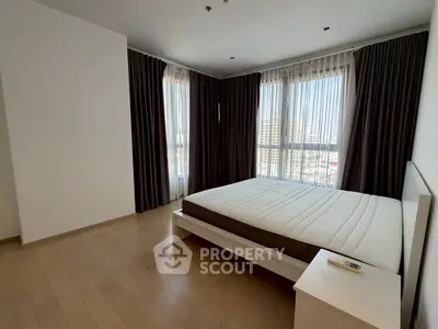 Spacious bedroom with large windows and modern decor in a high-rise apartment.