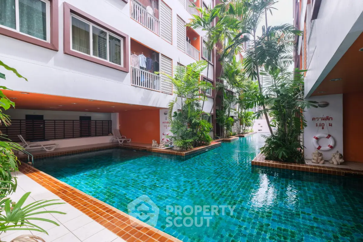 Luxurious apartment complex with a stunning outdoor pool surrounded by lush greenery.
