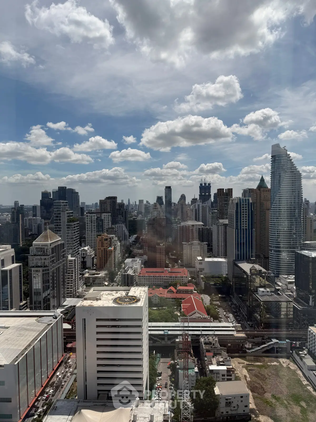 Stunning cityscape view from high-rise building with clear blue sky and modern skyscrapers.