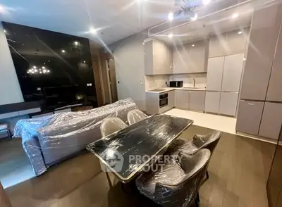 Modern open-layout living room and kitchen with sleek furniture and appliances.