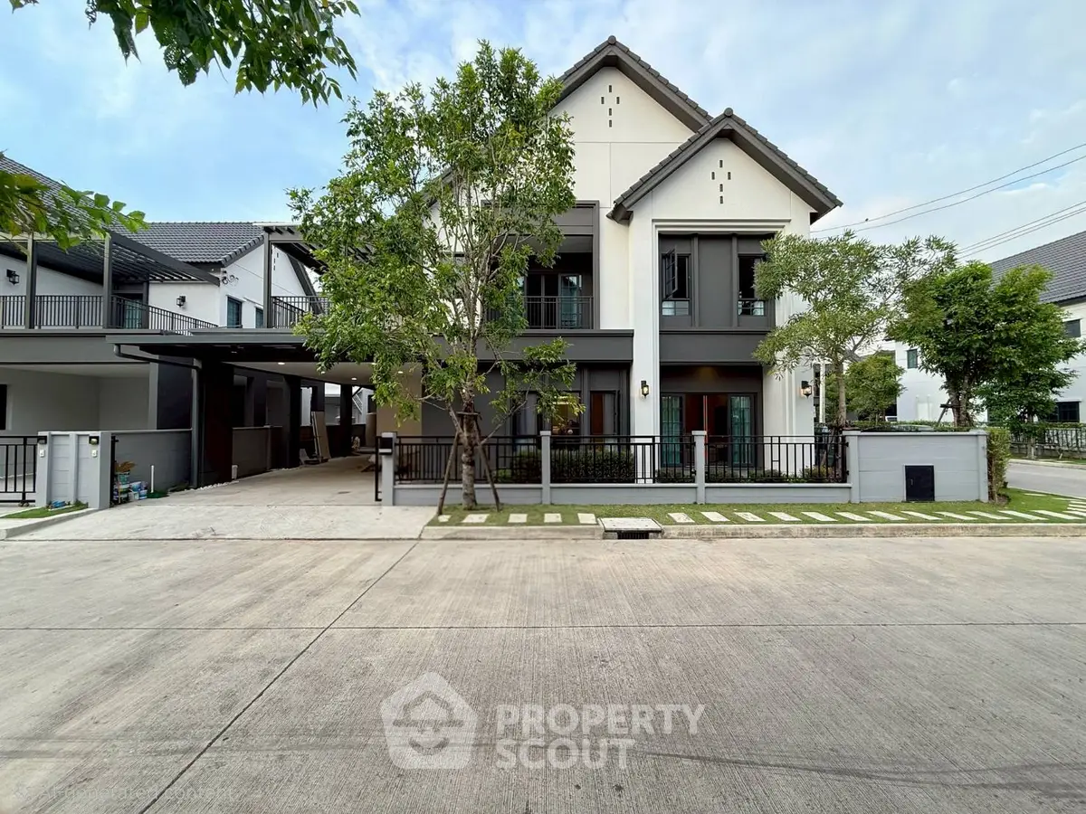 Modern two-story house with sleek design and spacious driveway in a suburban neighborhood.