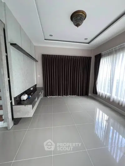 Spacious modern living room with large windows and elegant curtains