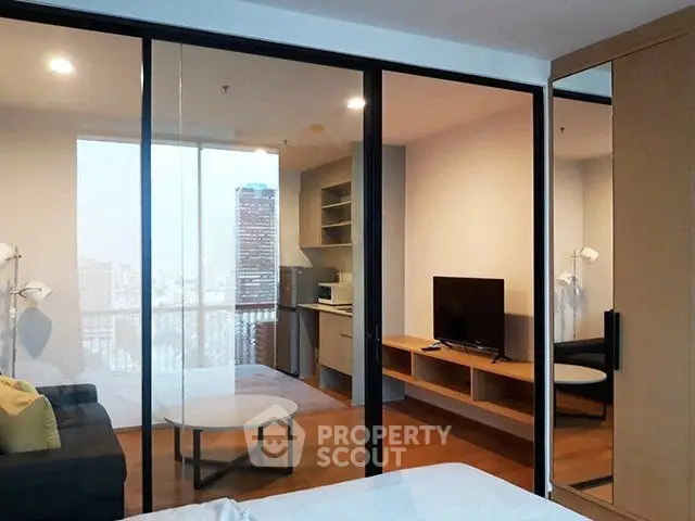 Modern apartment interior with glass partition, cozy living area, and city view.