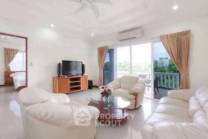 Spacious living room with plush white sofas and large windows offering a serene garden view.