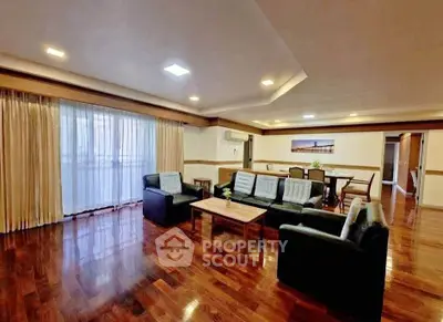 Spacious living room with elegant wooden flooring and modern furniture, perfect for family gatherings.