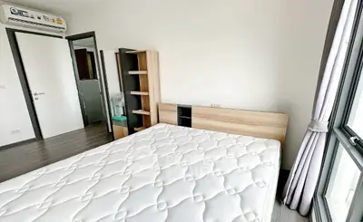 Modern bedroom with large window and minimalist furniture in a bright apartment.