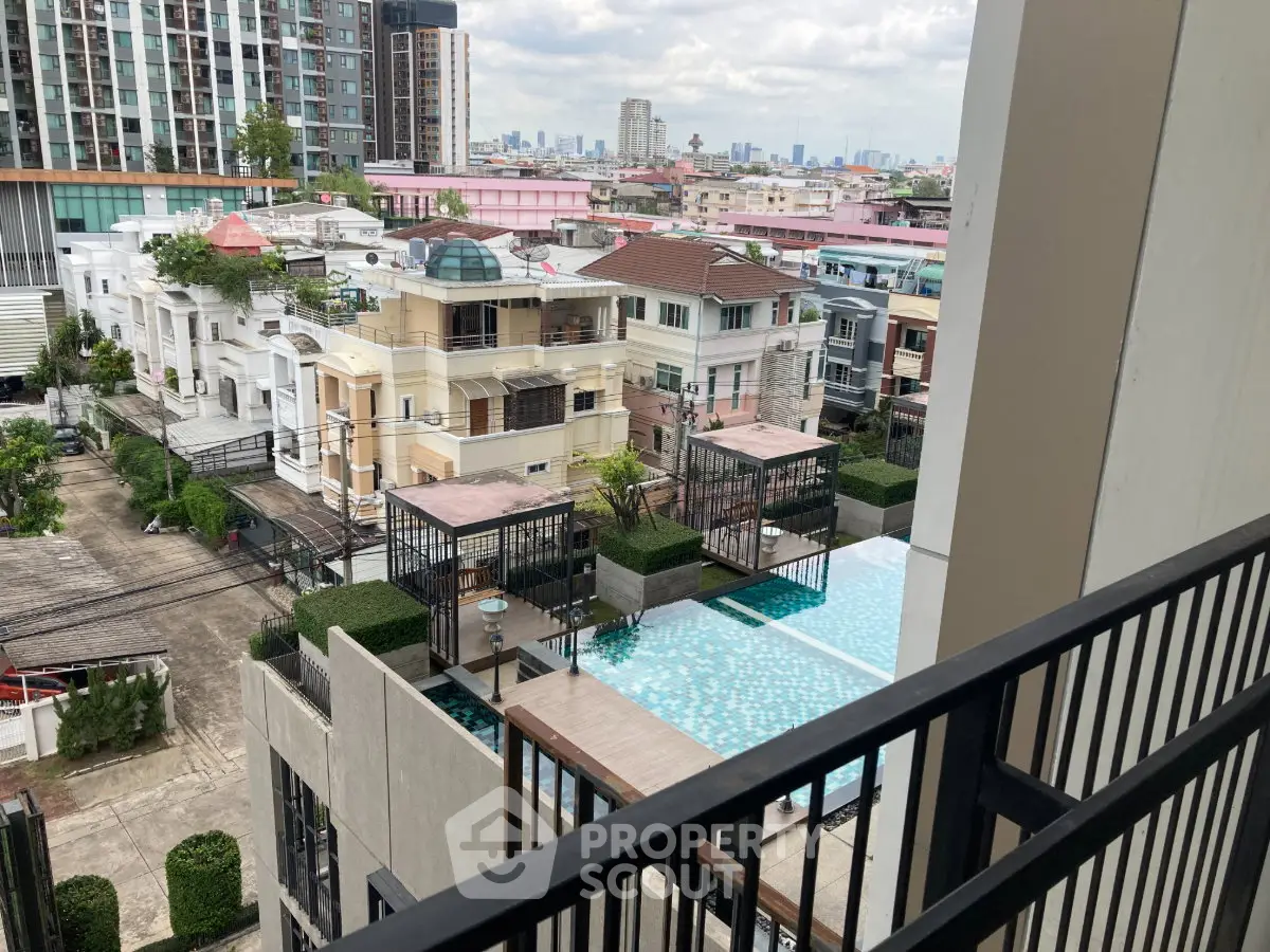 Stunning cityscape view from a modern balcony overlooking a luxurious pool and urban skyline.