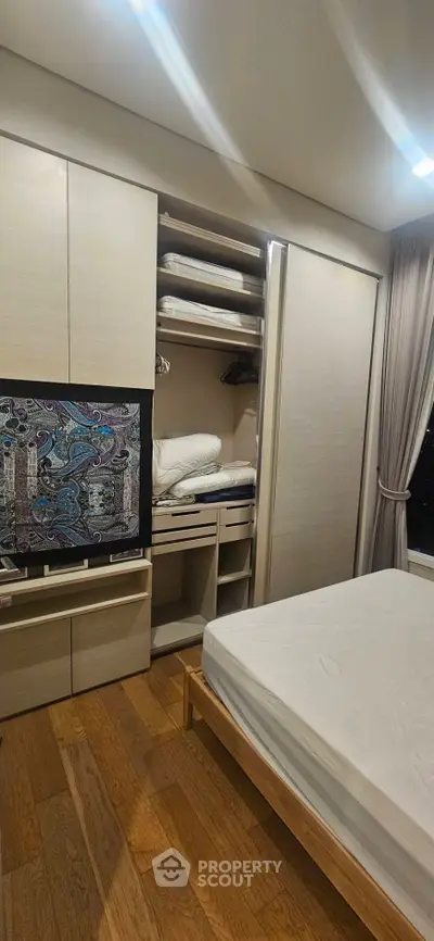 Modern bedroom with built-in wardrobe and wooden flooring, showcasing sleek design and ample storage space.