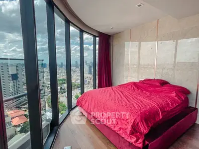 Luxurious bedroom with panoramic city view and elegant red bedding.